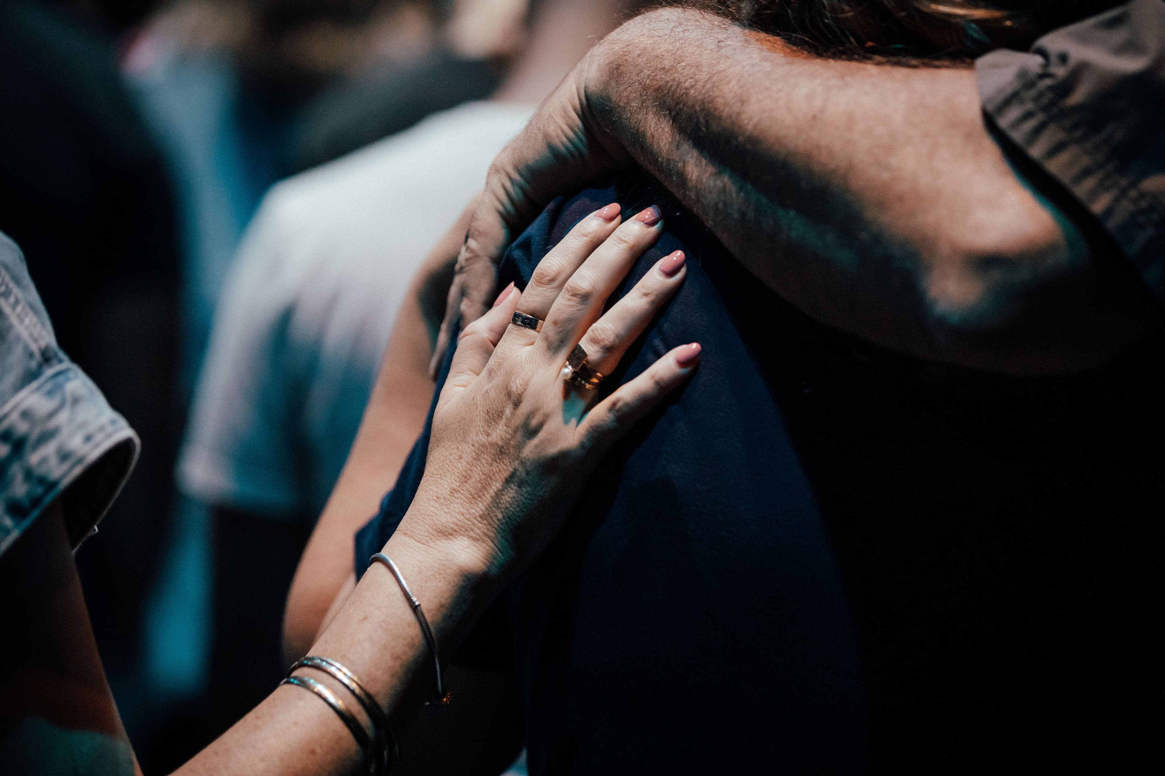 Person being prayed for from behind with a woman's hand on their back