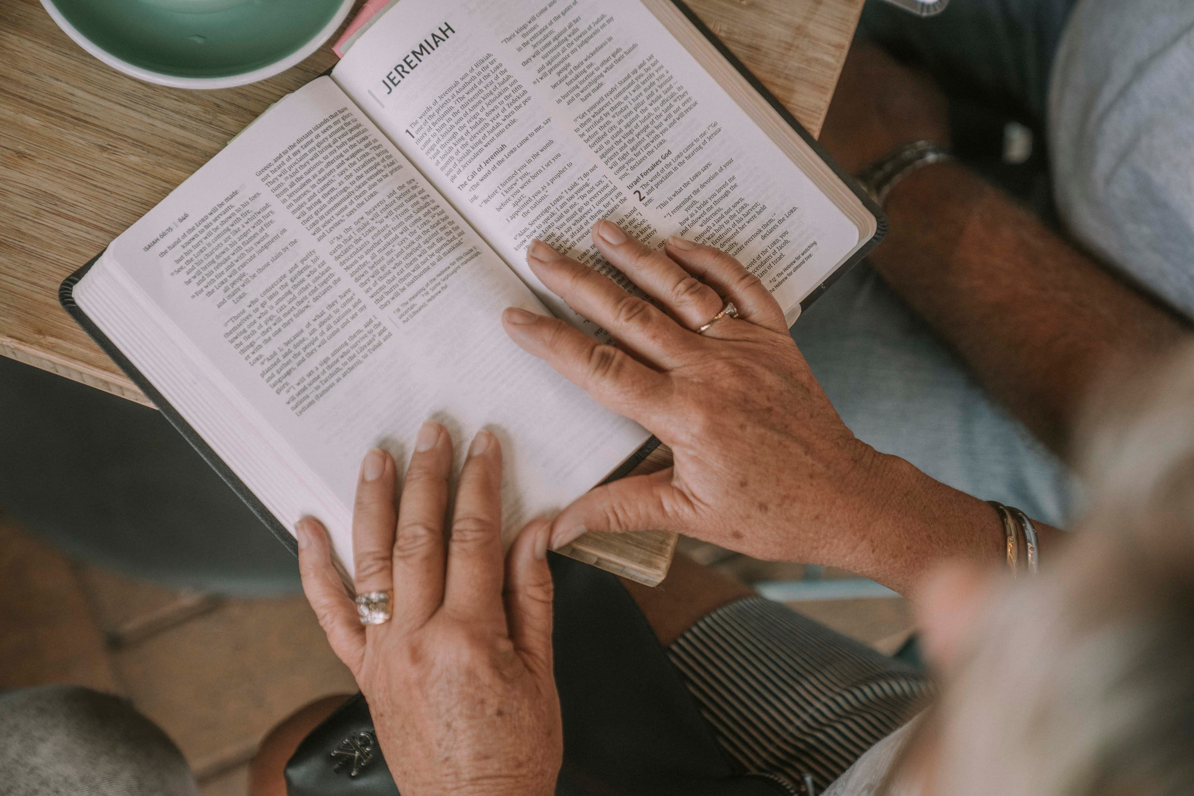 Woman's hands resting on an open bible on a table