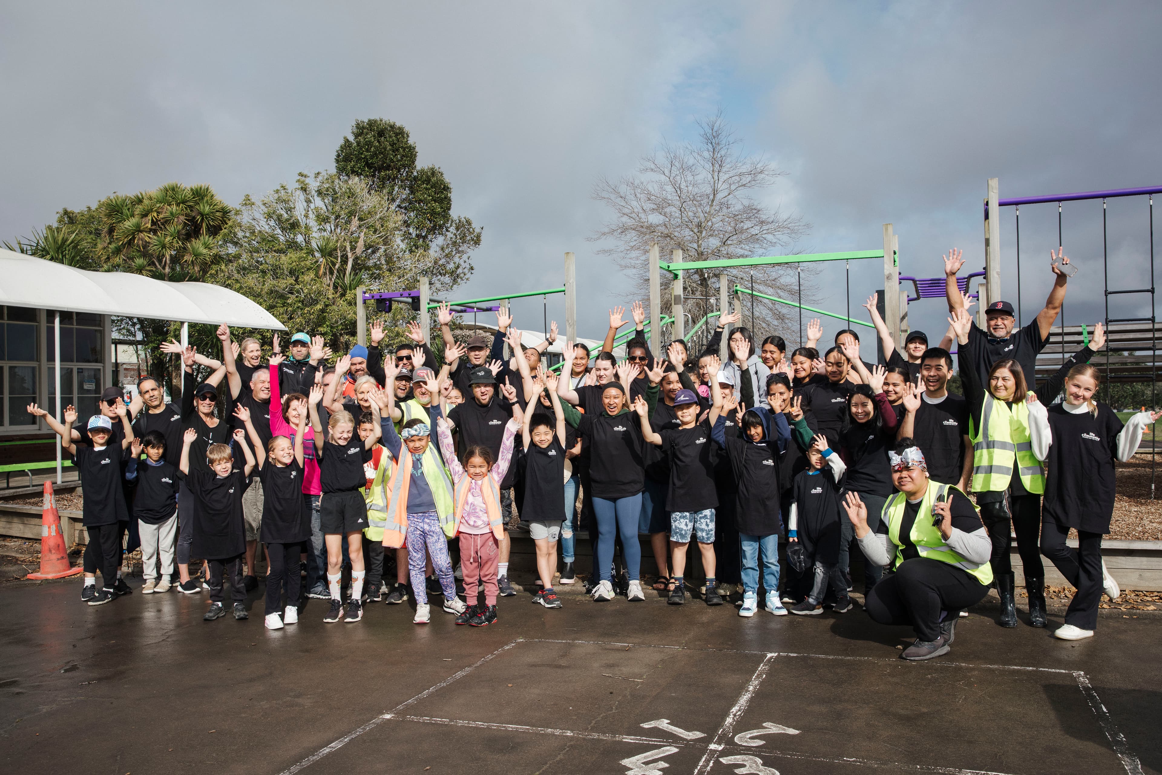 Volunteers for a Help & Hope Week project at a school smiling and with hands up