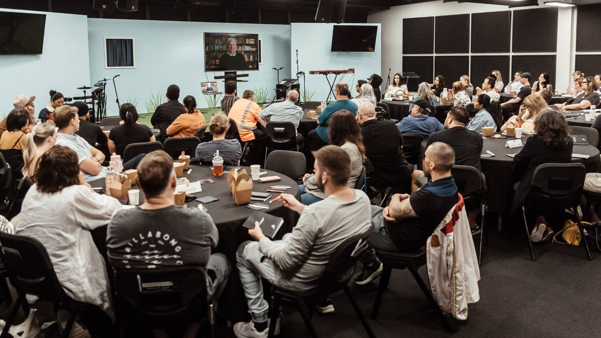 Room full of people watch a video on a large TV in the Alpha course