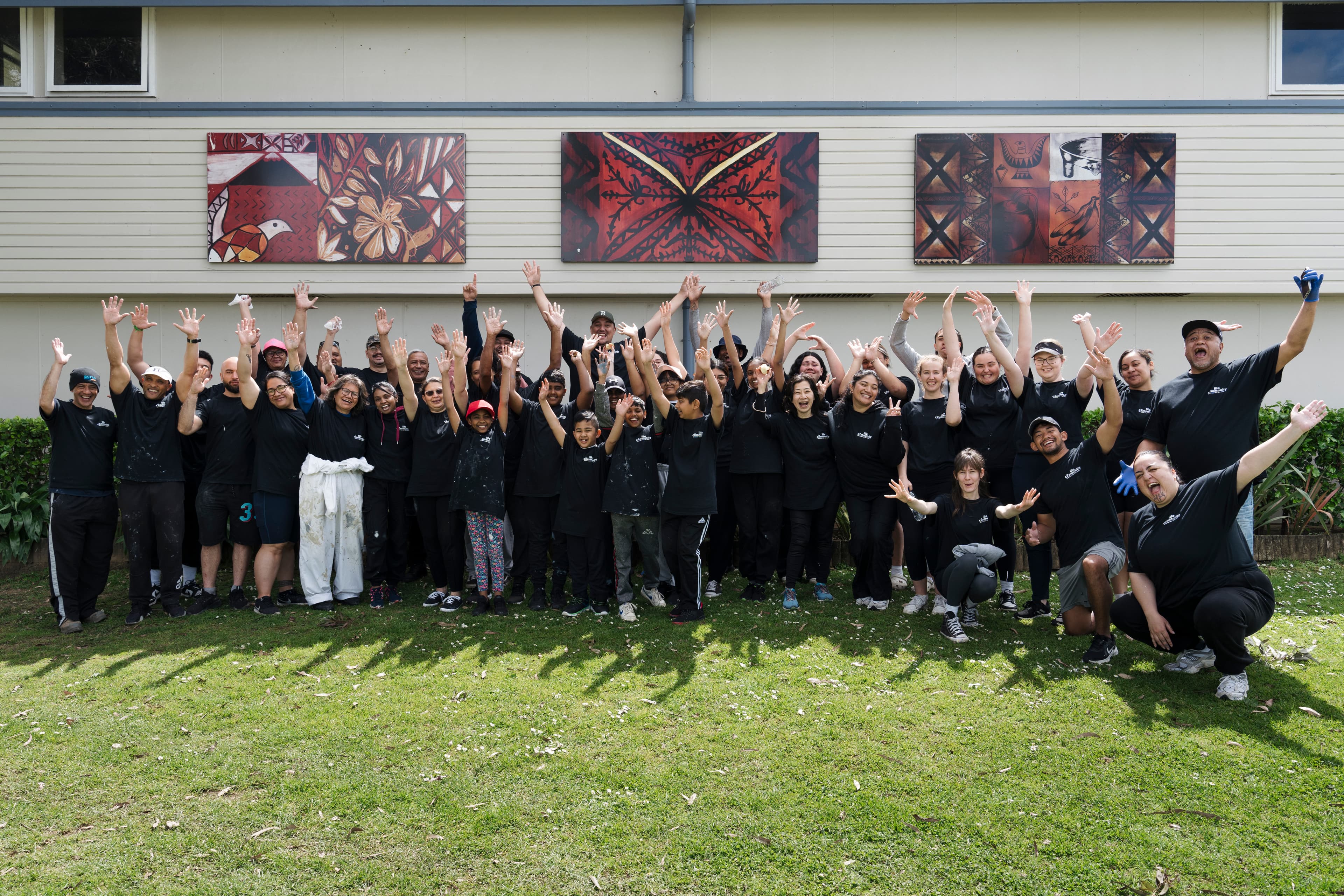 Large group of people outside a school in matching Help and Hope Week t-shirts after completing a painting and tidy up project