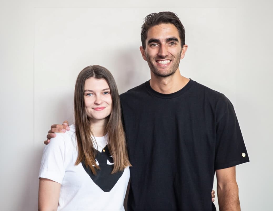 Logan and Bryar smiling and looking at the camera in a white t-shirt (her) and black t-shirt (him)